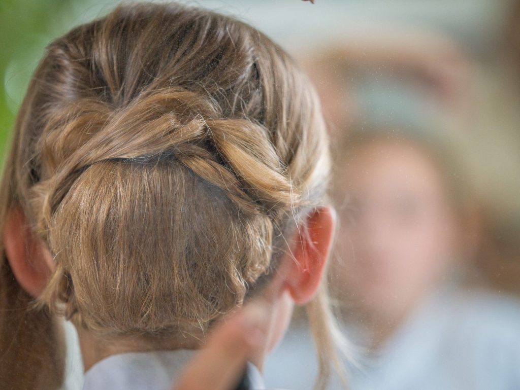 Vue de derrière la tête de la mariée en train de se préparer pour son mariage, avec sa coiffure élégante en cours de finition.